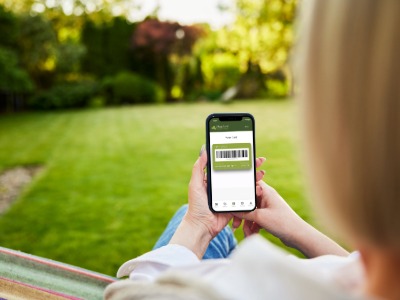 Woman holding mobile phone looking at Thetford Garden Centre loyalty app